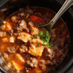 A steaming bowl of hearty beef stew garnished with fresh herbs, surrounded by chunks of tender beef, carrots, potatoes, and celery, served in a rustic ceramic bowl on a wooden table, with a spoon resting beside it and a warm, inviting atmosphere.